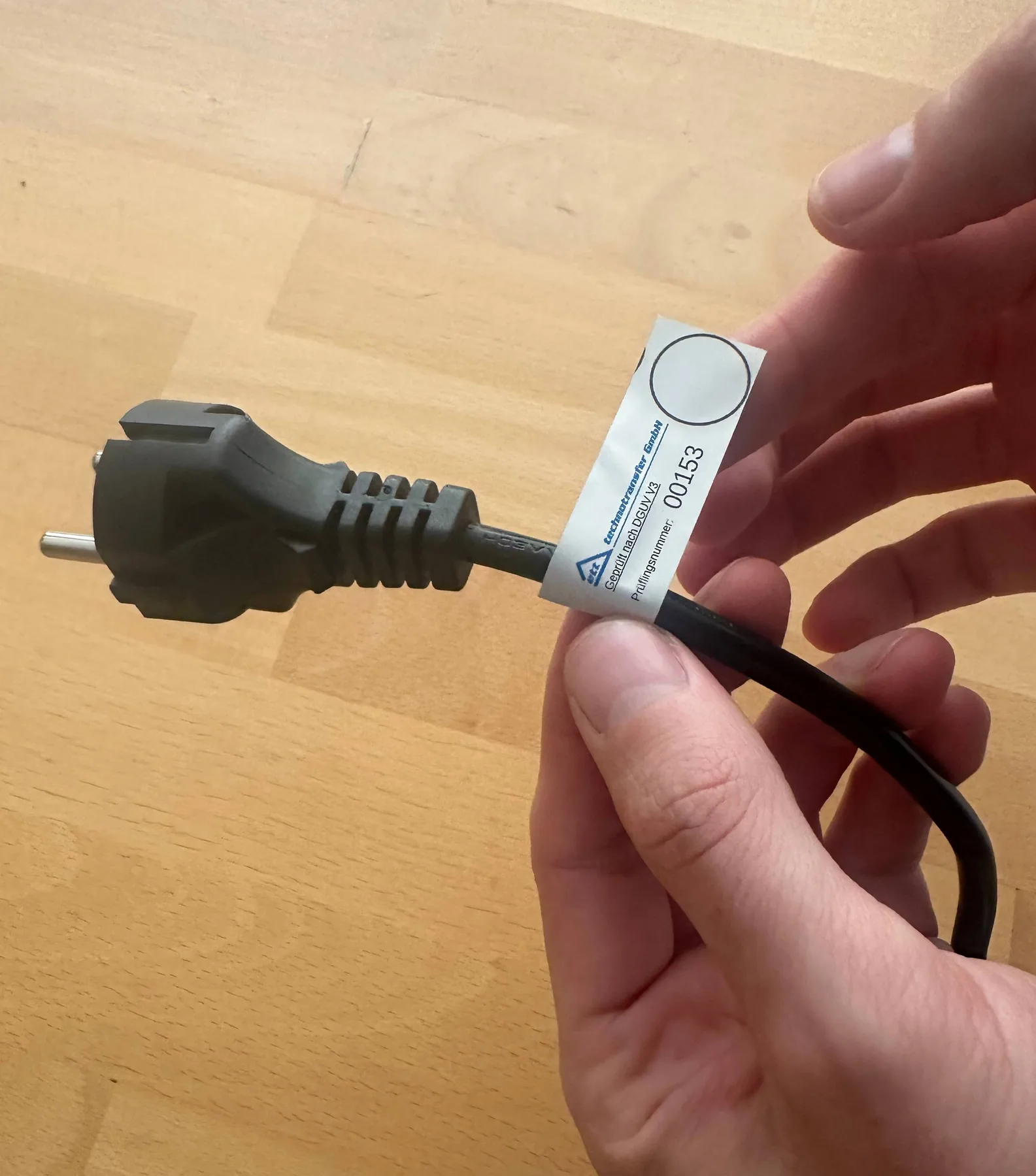 Prüfplakette der ett technotransfer GmbH mit Prüflingsnummer an einem geprüften Netzkabel